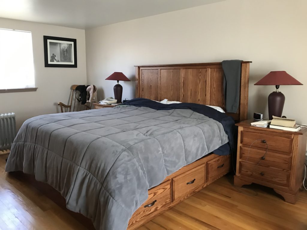 bedroom with wood bed and gray blanket before listing and home staging