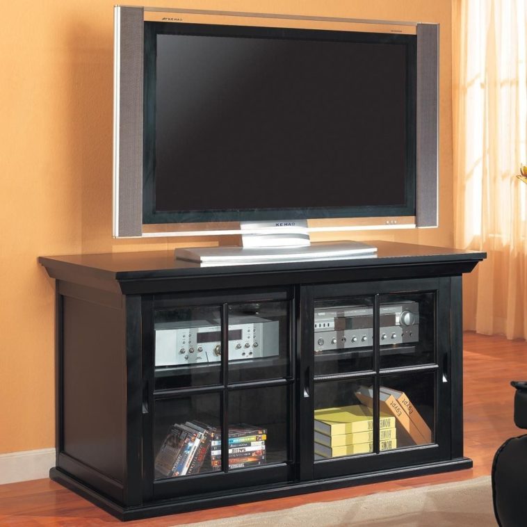 black-stained-wood-tv-stand-and-media-storage-unit-with-glass-door-placed-on-brown-laminate-wooden-floor